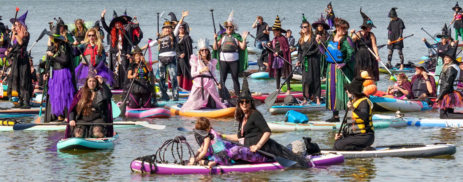 People dressed as Witches and Warlocks on Stand-Up paddle boards afloat in the Hudson River at the SUP Witches Festival